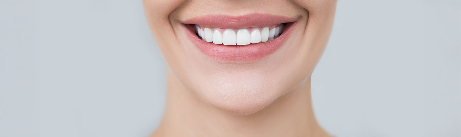 The image features a person with a smiling expression, showcasing their teeth and facial features against a neutral background.