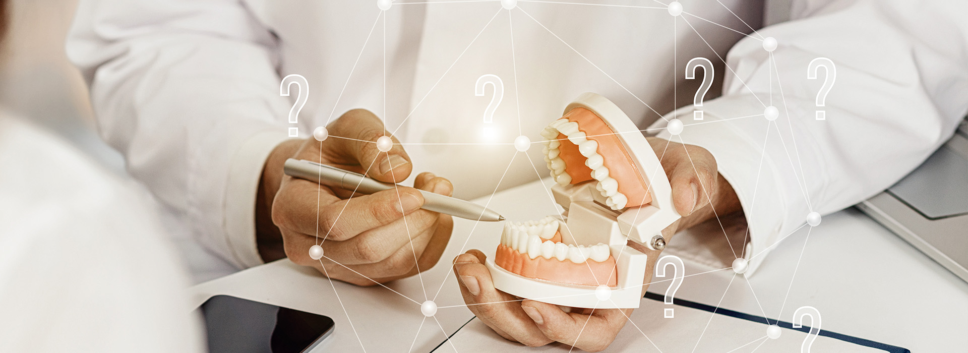 A dental professional holding a model of teeth and gums, with digital overlays displaying diagnostic information.