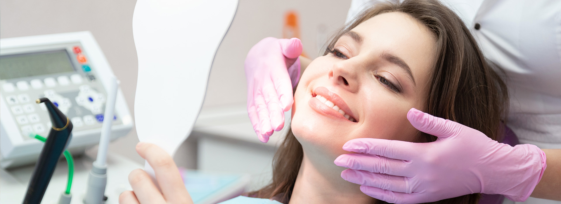 A woman receiving dental care in a chair, with a dentist working on her teeth.